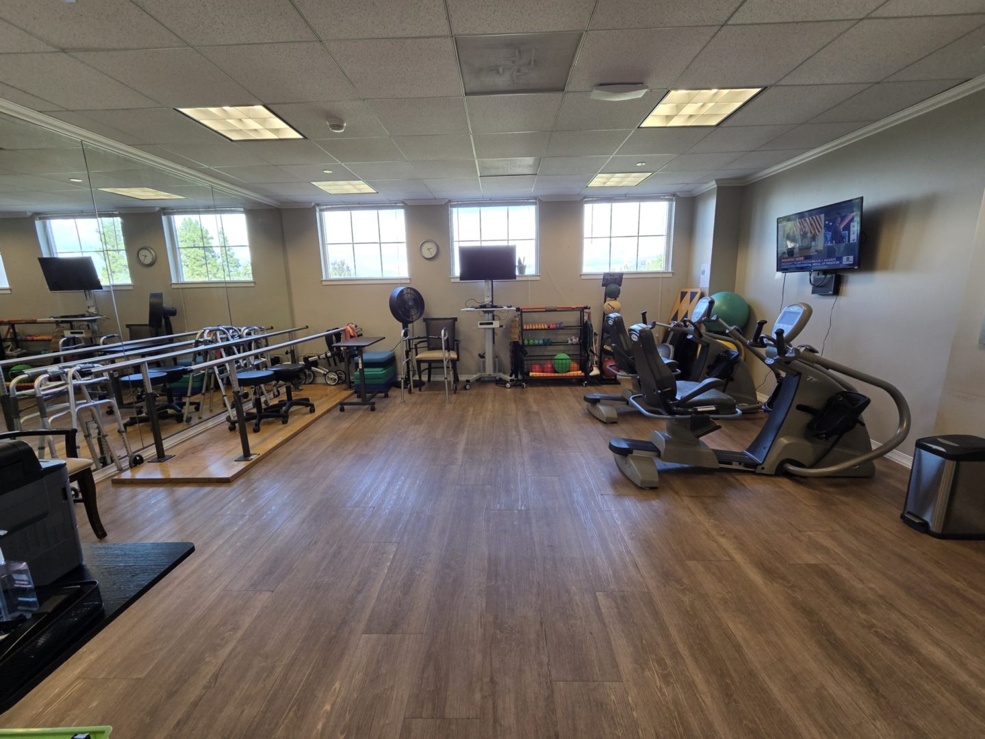 Rehabilitation gym with exercise equipment and mirrors.