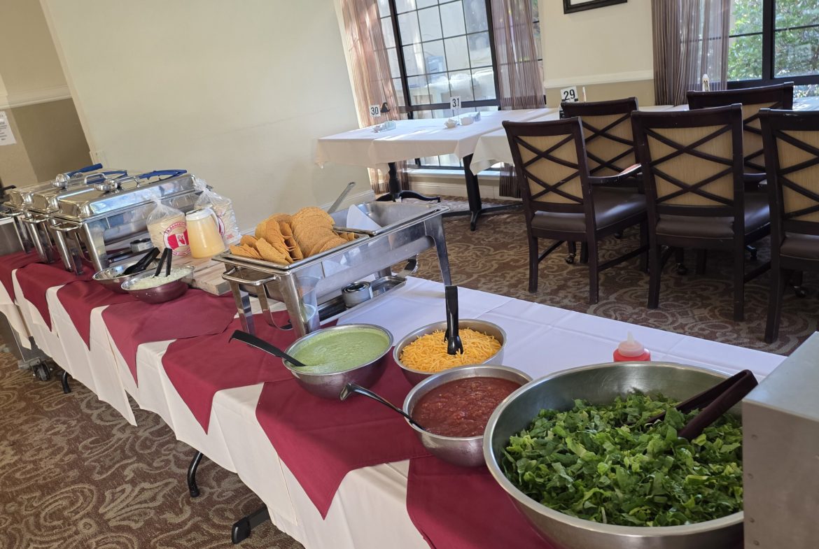 Buffet table with tacos and condiments.