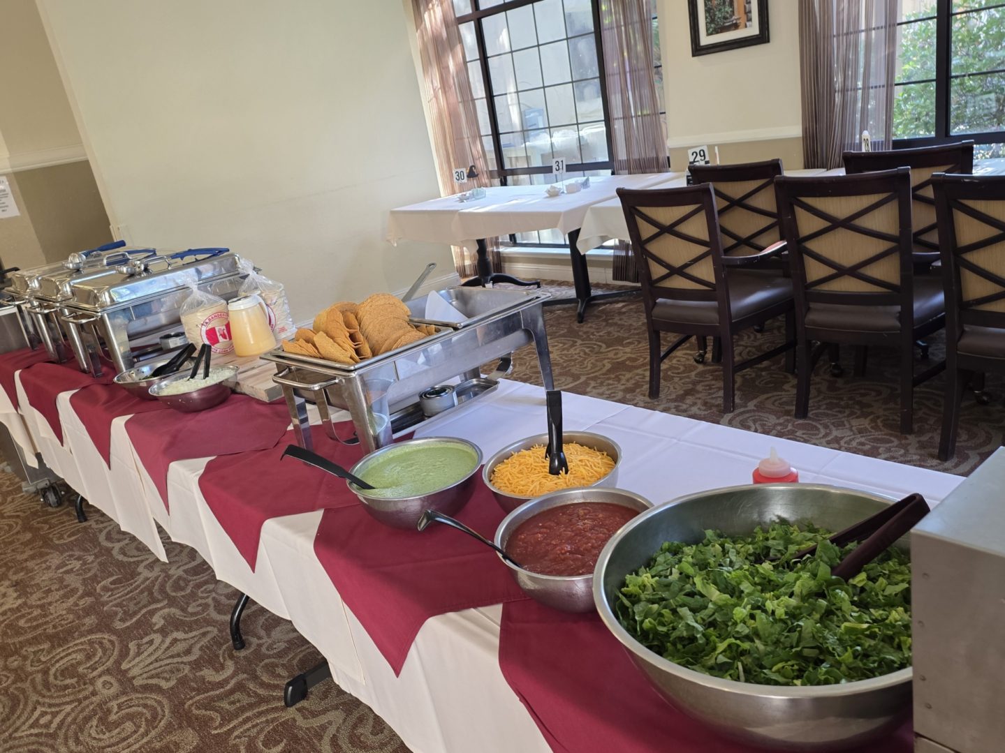 Buffet table with tacos and condiments.