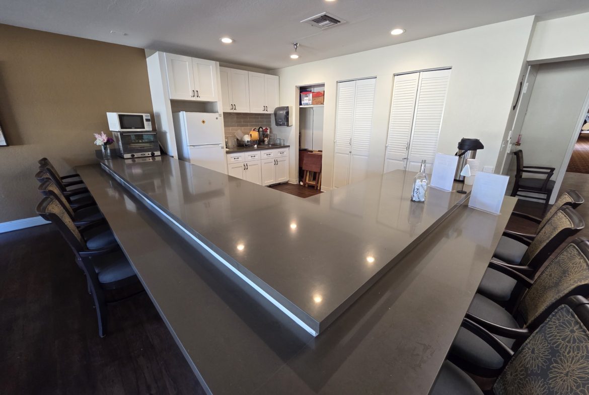 Spacious kitchen with long countertop and chairs.