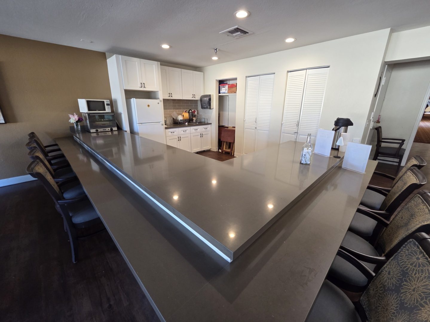 Spacious kitchen with long countertop and chairs.