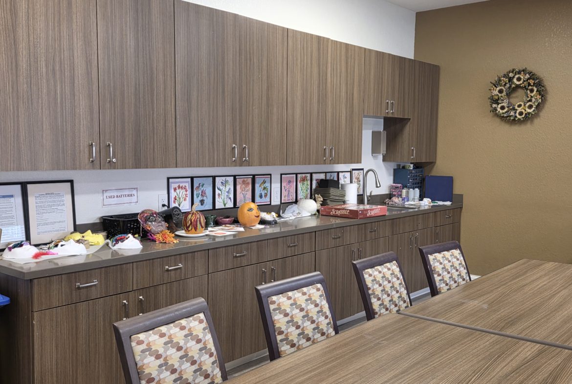Office kitchen with cabinets and table setup.