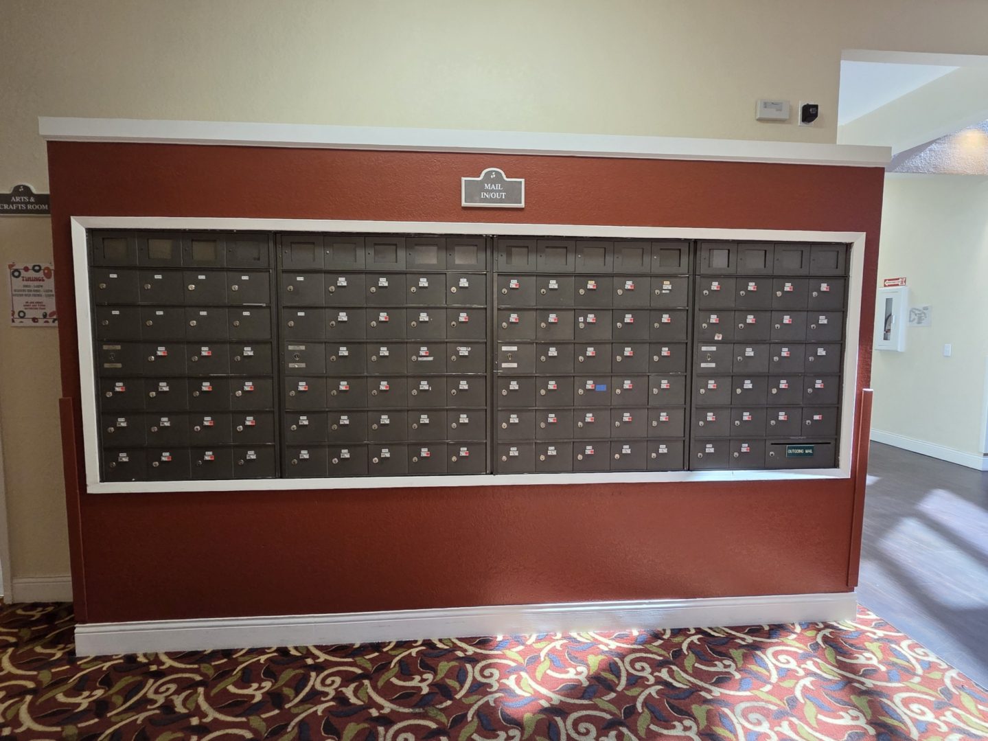 Wall of apartment mailboxes with carpeted floor.