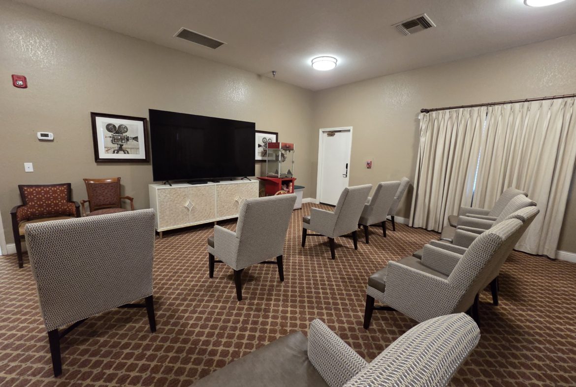 Room with chairs facing large television screen.