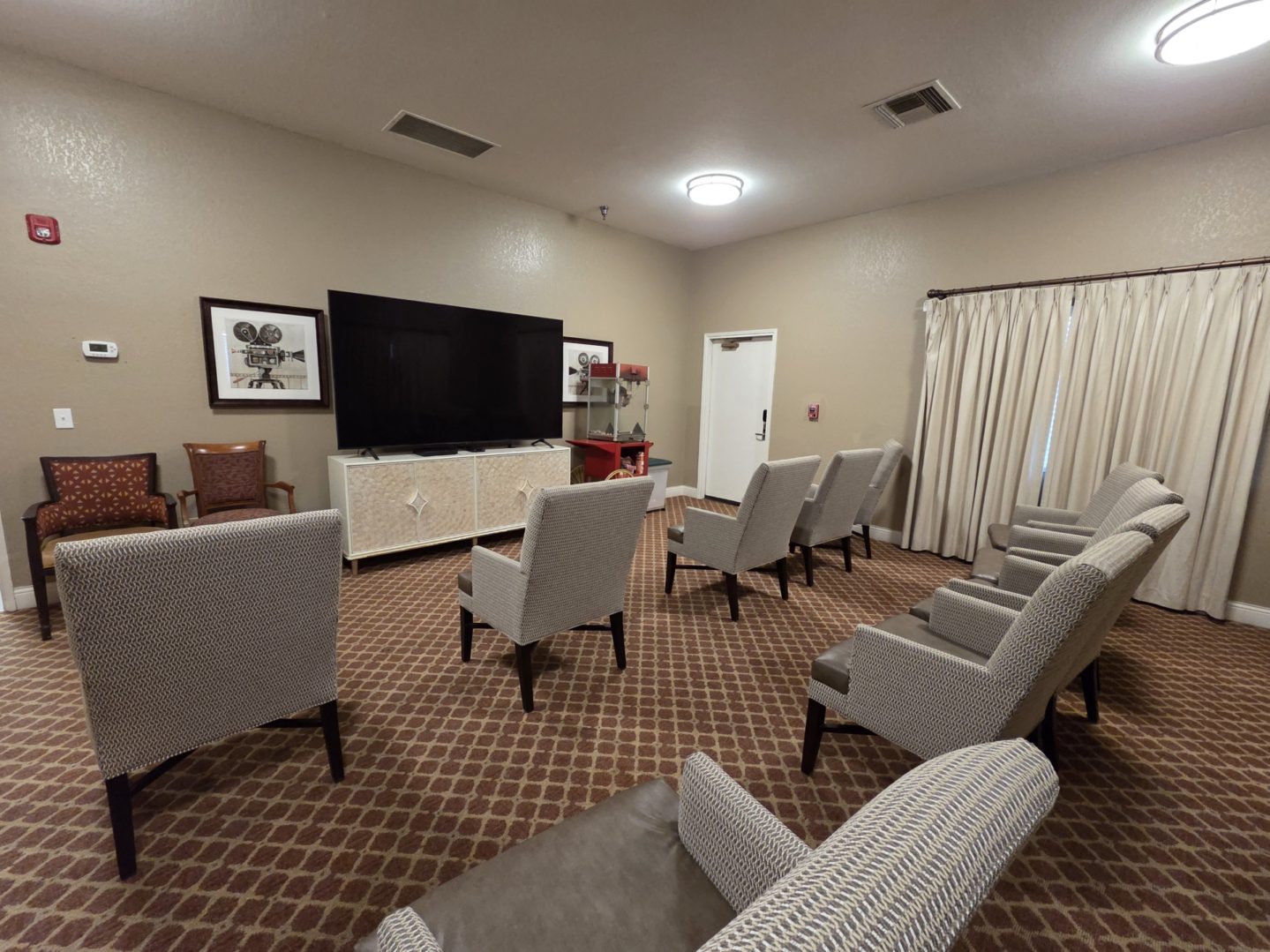 Room with chairs facing large television screen.