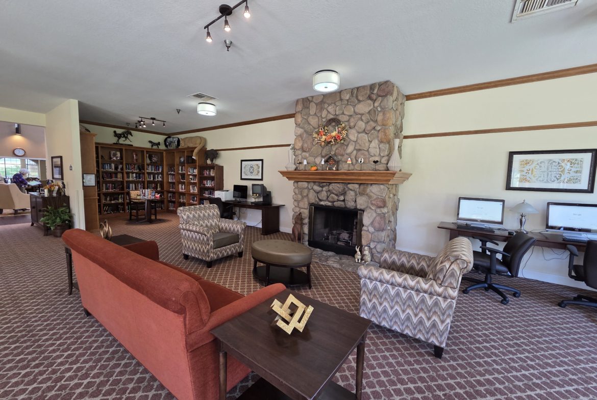 Cozy library lounge with fireplace and computers.
