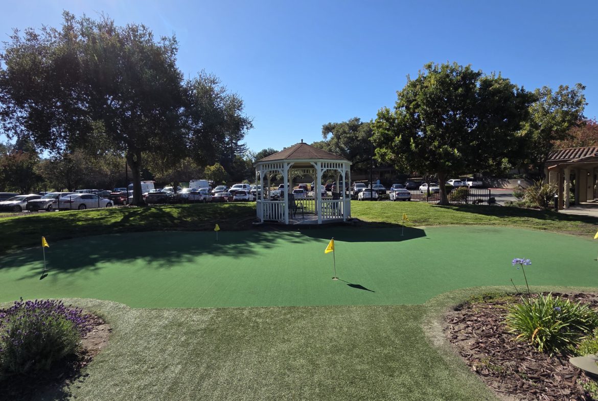 Gazebo on mini golf course under clear sky.