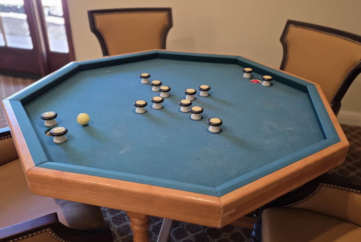 Octagonal carrom board with chairs around.