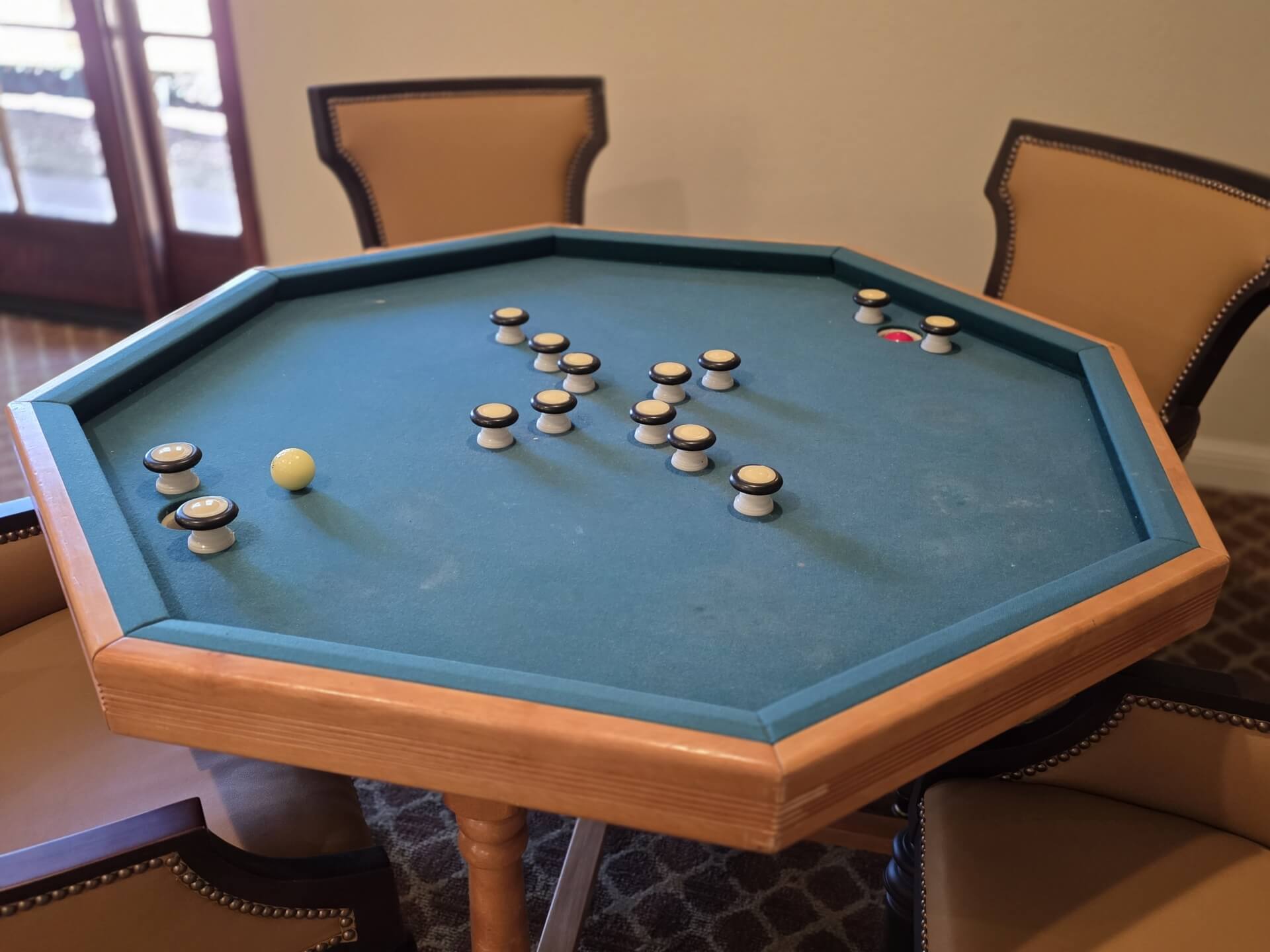 Octagonal carrom board with chairs around.