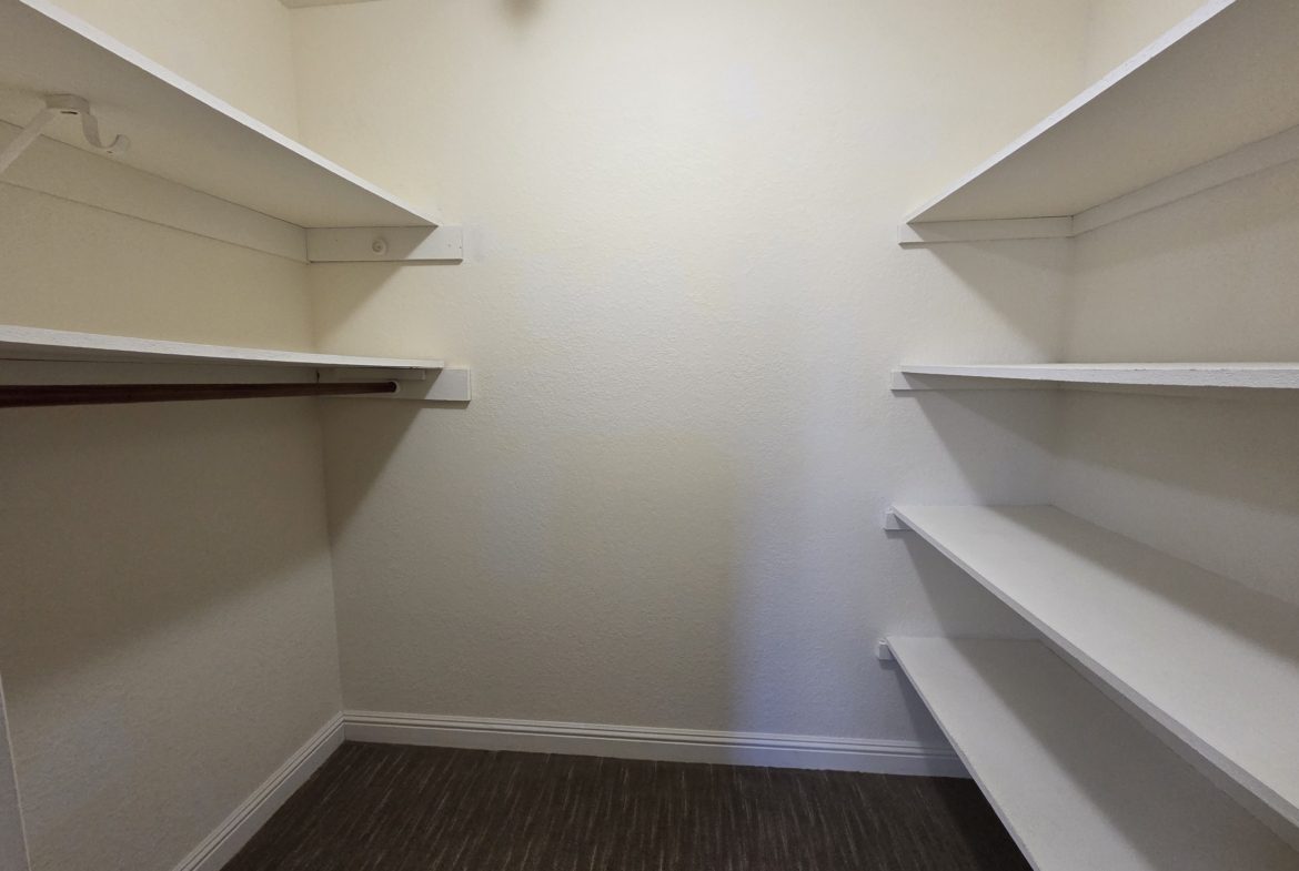 Empty walk-in closet with white shelves.