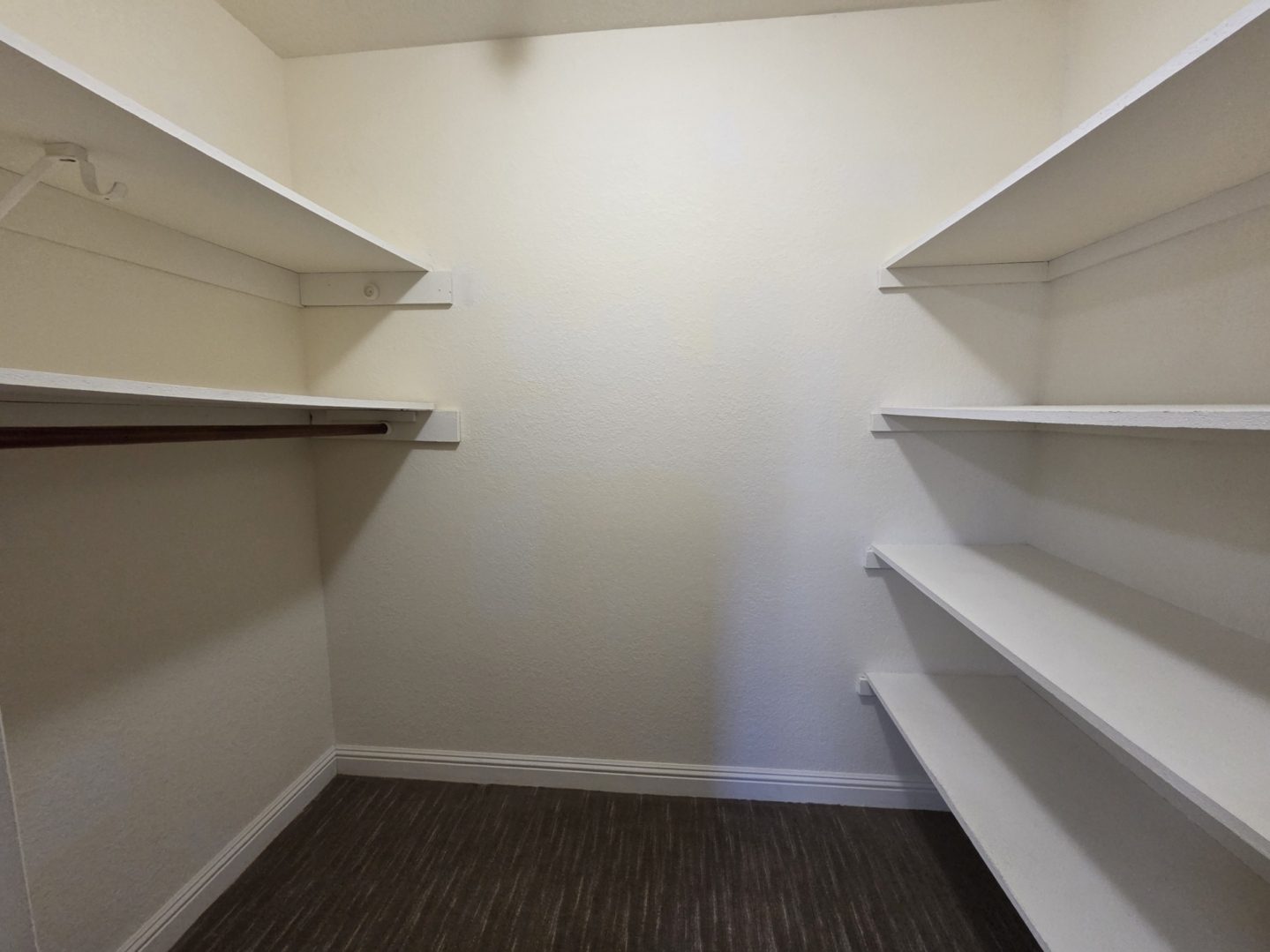 Empty walk-in closet with white shelves.